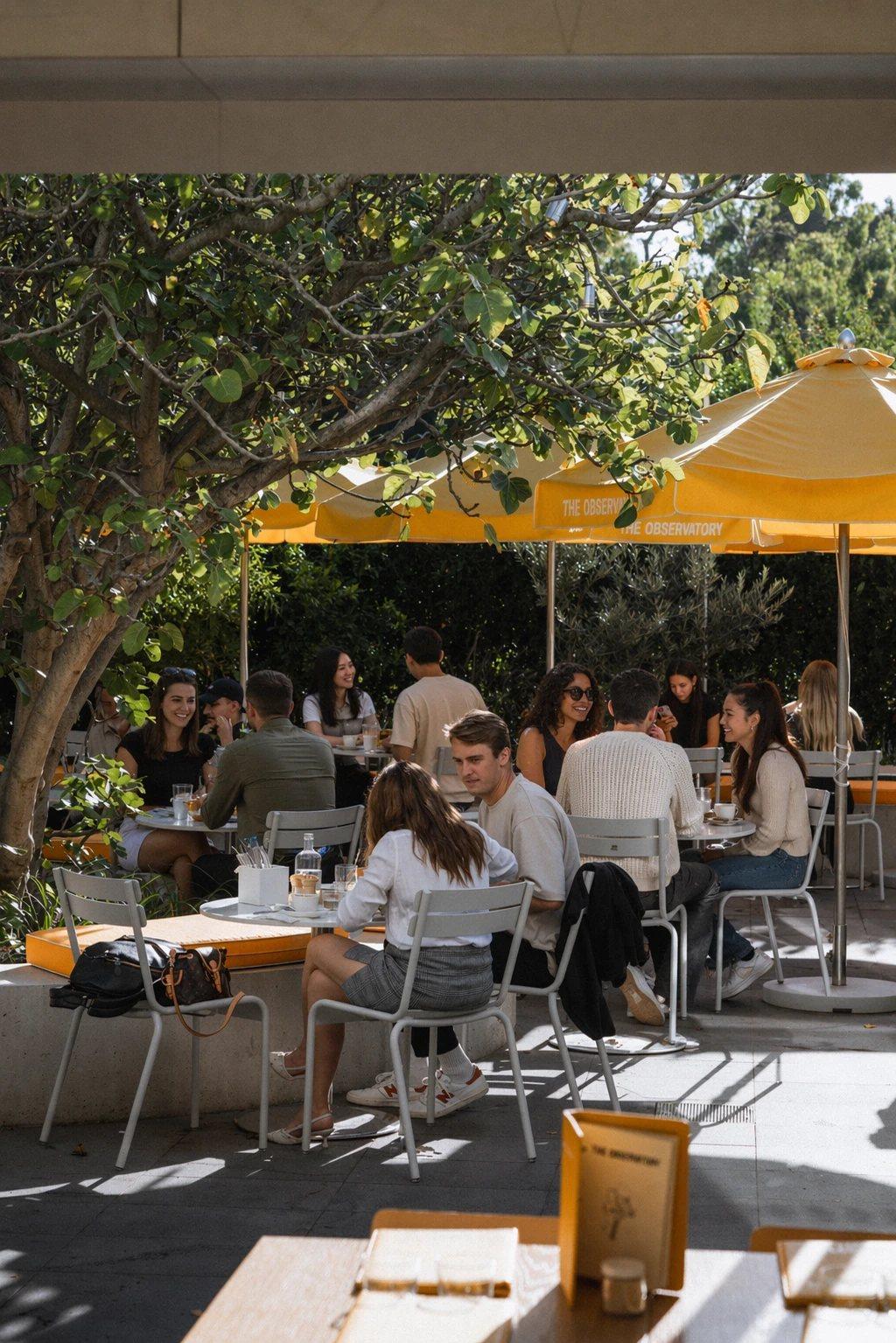 Guests dining in The Observatory courtyard under yellow umbrellas