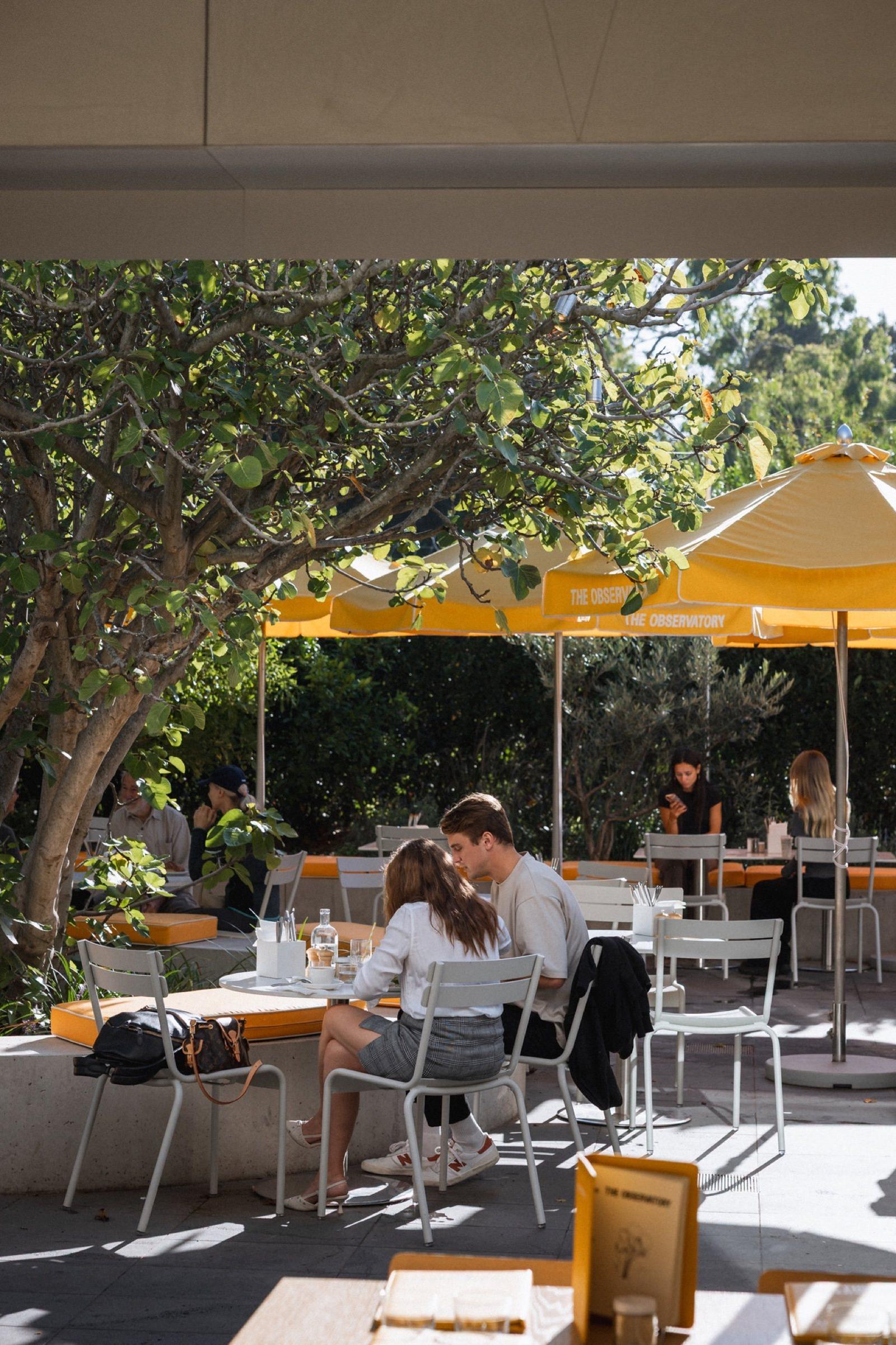 Diners in the courtyard under yellow umbrellas at The Observatory