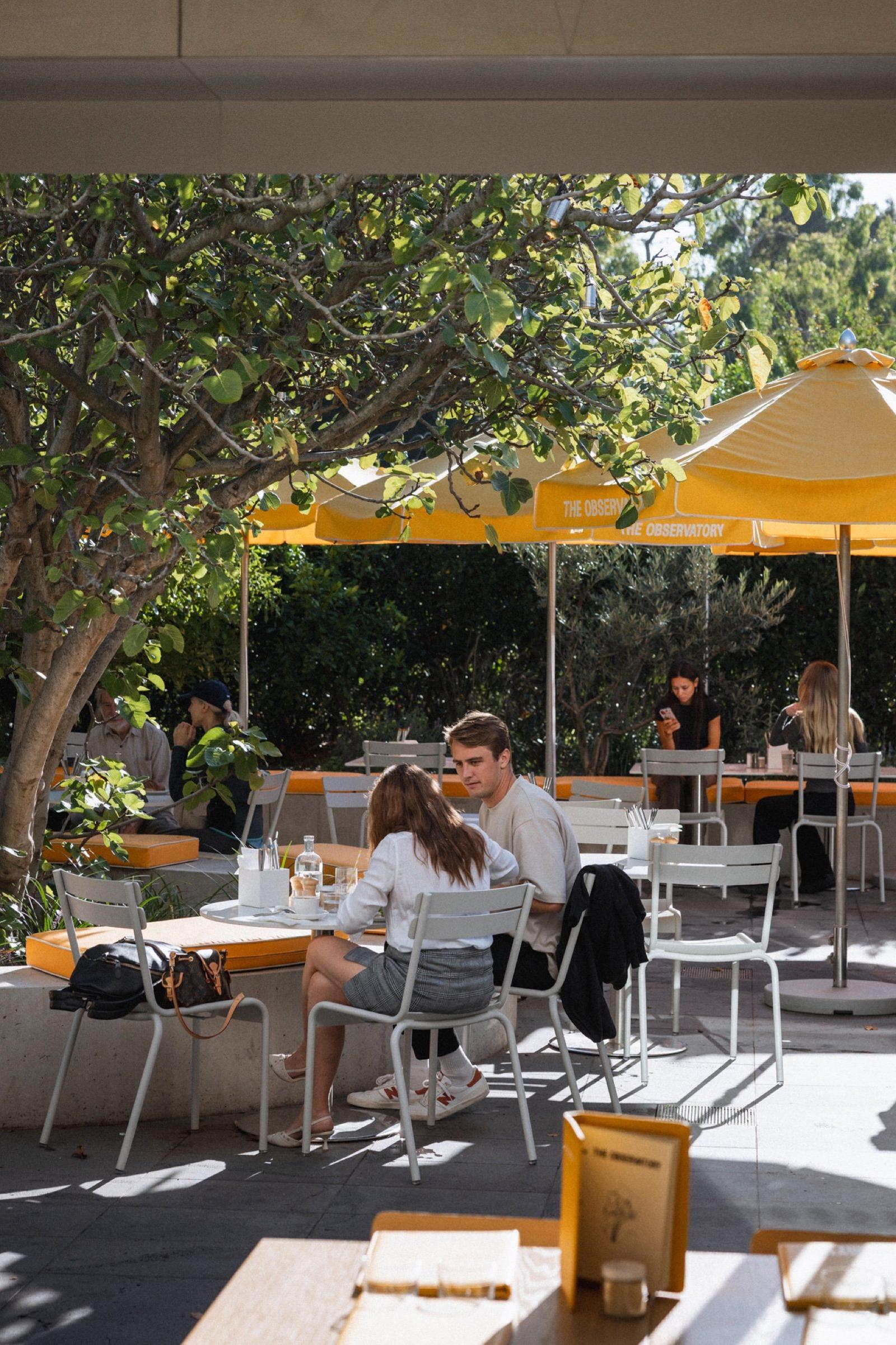 Diners in The Observatory courtyard under yellow umbrellas