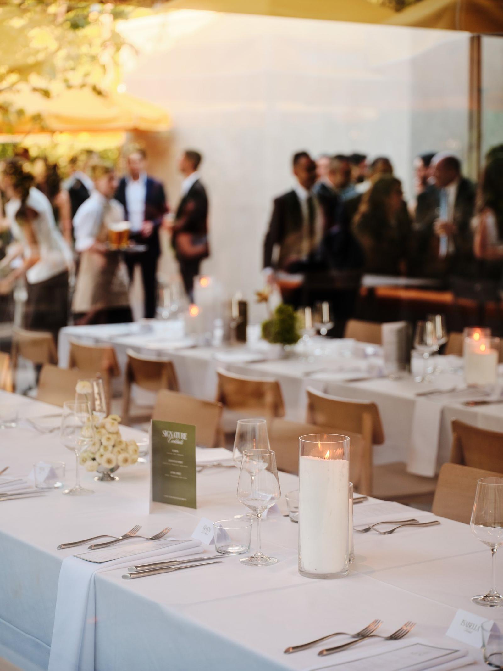 Guests gathering beside set long tables at an evening event