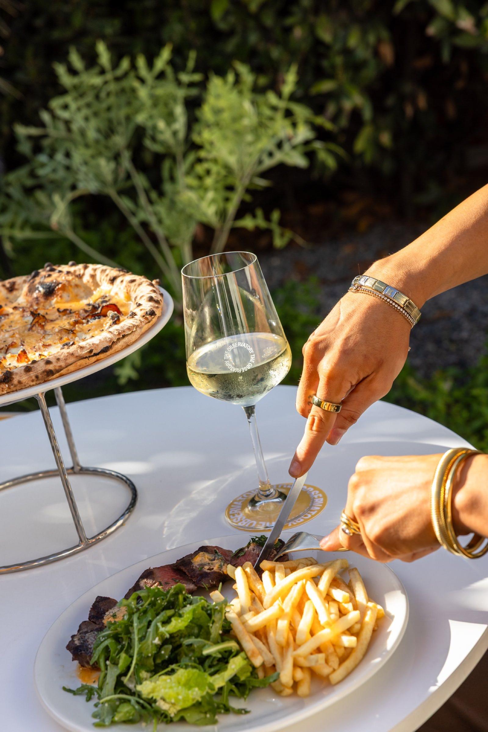 Steak frites and pizza on a garden table at The Observatory