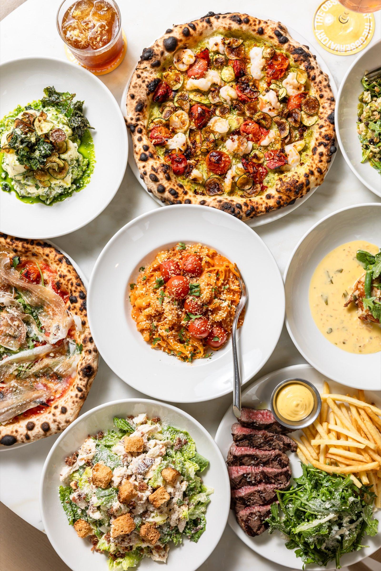 A table of pizza, pasta, salads and steak frites at The Observatory