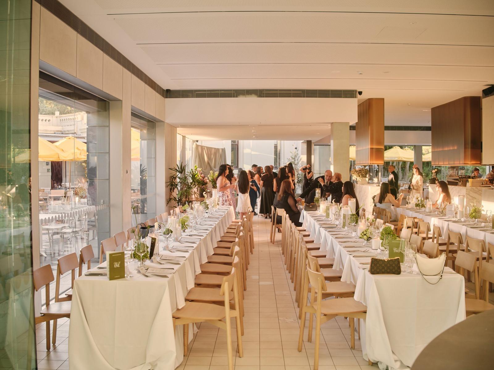 Long tables set end to end through the glass-walled dining room