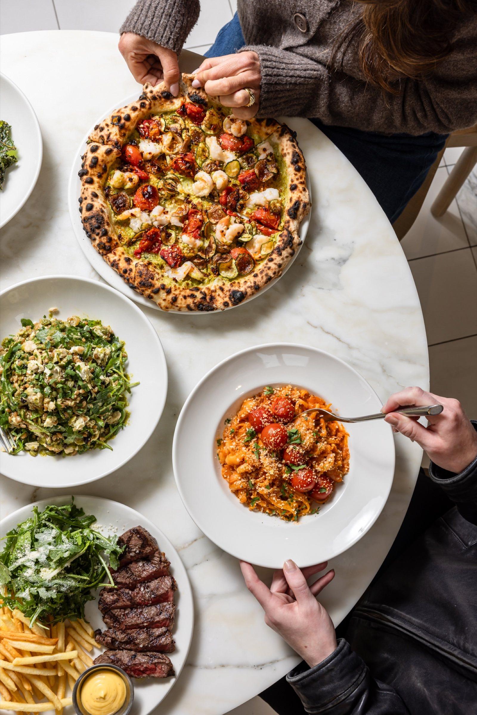Friends sharing pizza, pasta and salads at The Observatory