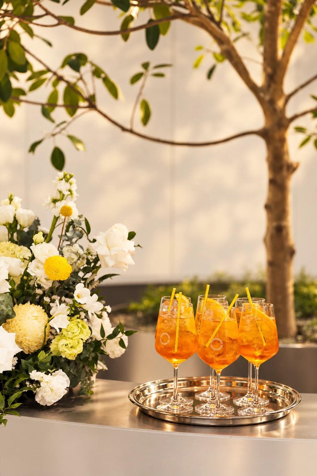 Spritz on a silver tray beside florals and the tree atrium at The Observatory