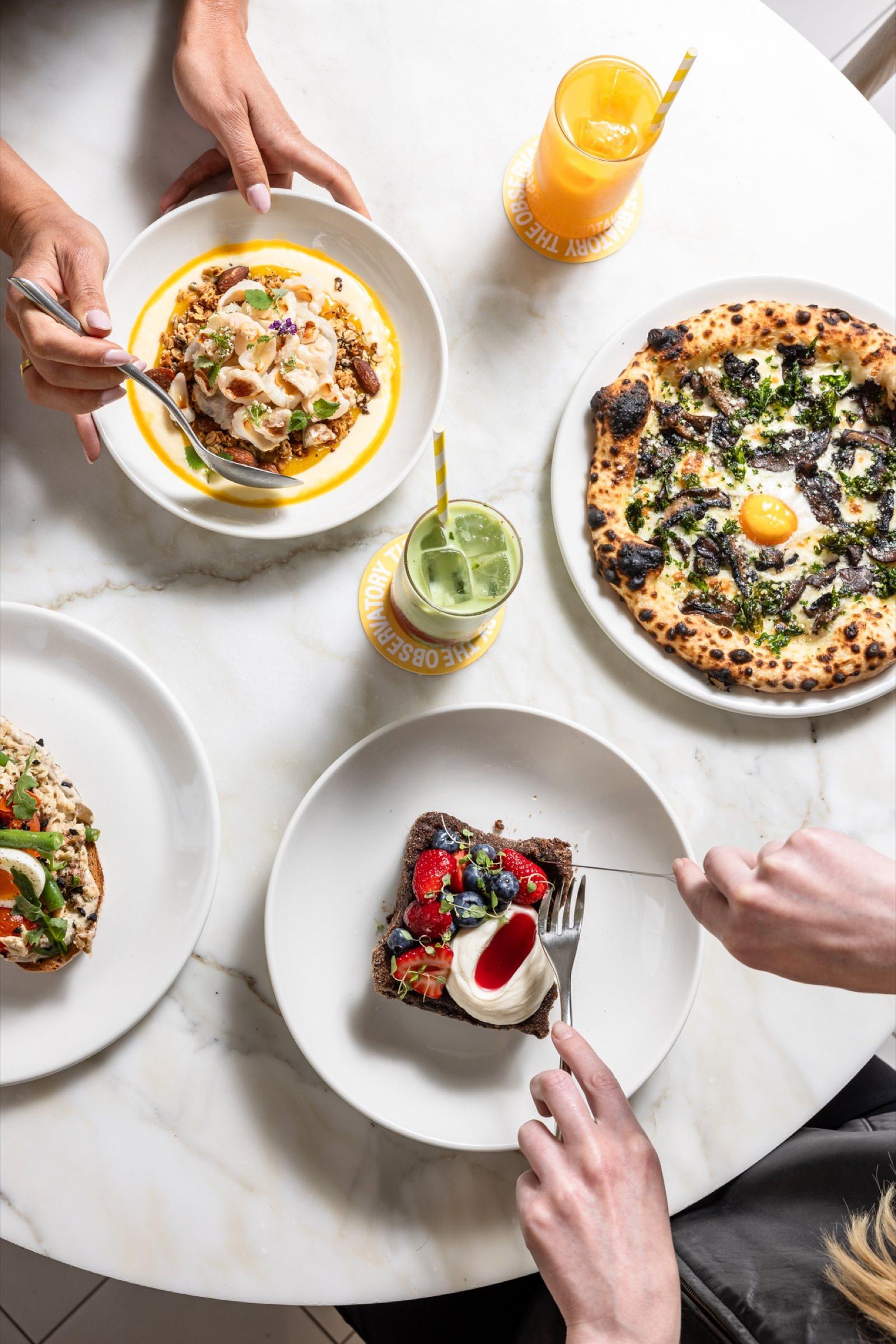 Friends sharing breakfast and pizza at The Observatory