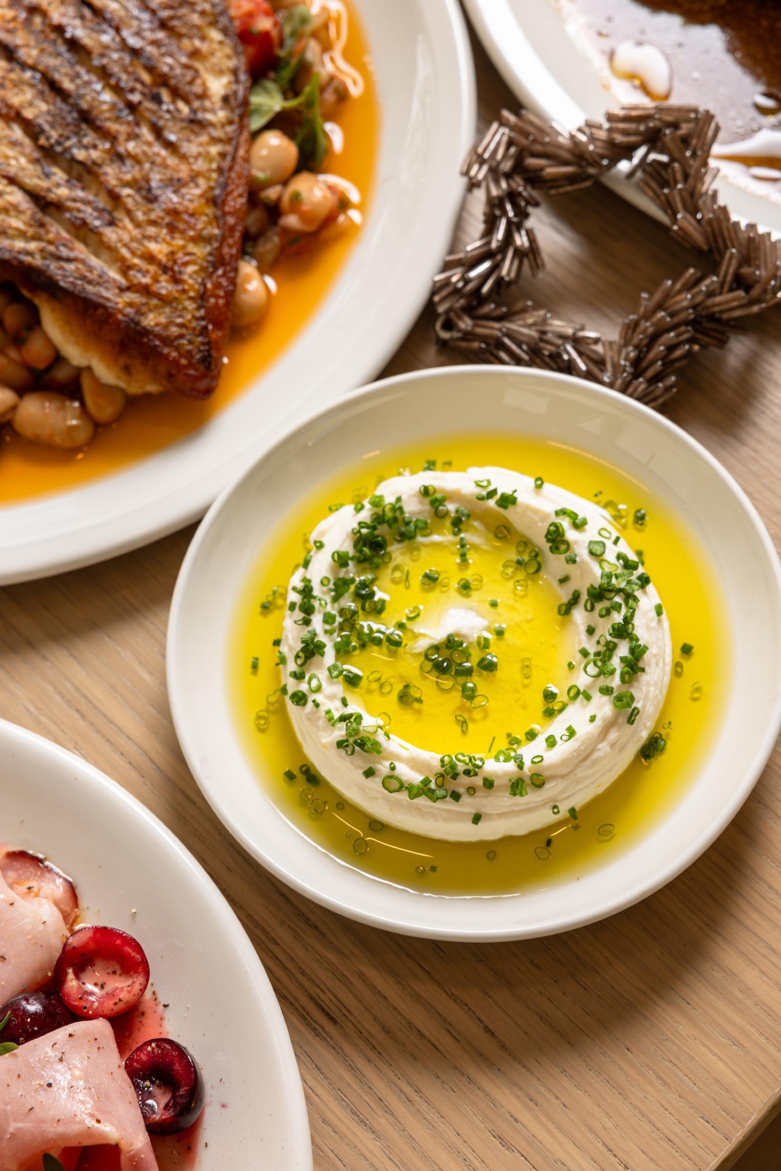 Whipped curd with chives and olive oil beside snapper and ham